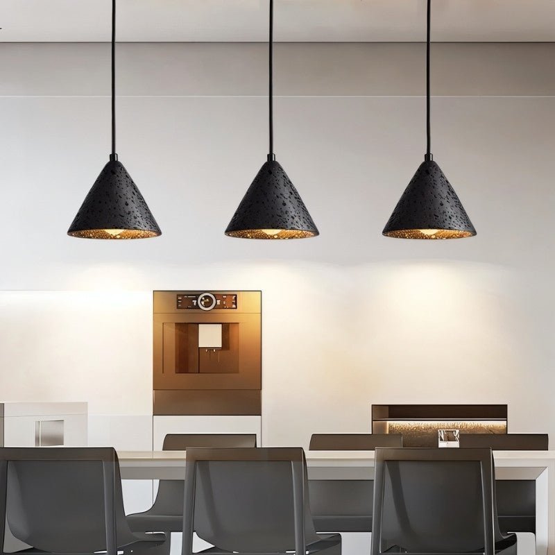 "Three conical black travertine pendant lights hanging above a kitchen island, providing warm lighting."