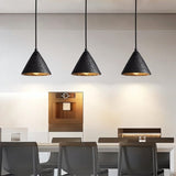 "Three conical black travertine pendant lights hanging above a kitchen island, providing warm lighting."