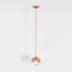 Copper pendant light with spherical glass shade hanging from a long cord against a white background.