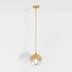 Brass pendant light with amber glass dome shade on white background.