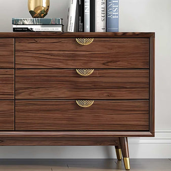 "Gold leaf-shaped drawer pulls on a modern wooden dresser in a living room."