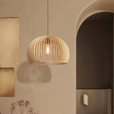 "Wooden pendant light with slatted dome design, hanging gracefully beside an arched wall, casting a warm and inviting glow in contemporary interiors."
