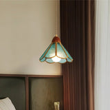 "Handcrafted blue glass pendant light with copper trim hanging in a bedroom setting, providing a warm, ambient glow."