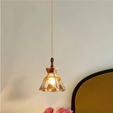"Handcrafted vintage-style pendant light with amber stained glass hanging in a bedroom, casting a warm glow."