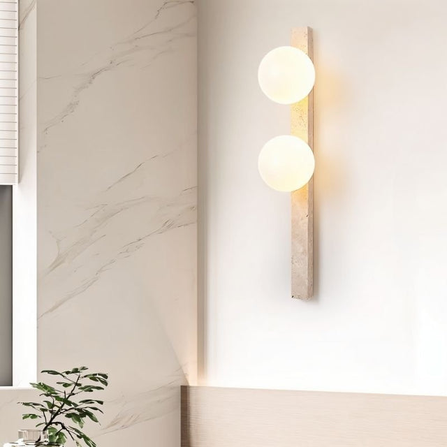 "Elegant travertine wall lamp with frosted glass globes mounted in a bathroom interior"