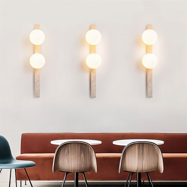 "Minimalist travertine wall lamps with frosted glass globes installed in a dining area"