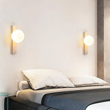 "Modern travertine wall lamps with frosted glass globes installed on both sides of a bed"