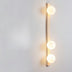 "Sleek travertine wall lamp with three frosted glass globes installed on a minimalist wall"