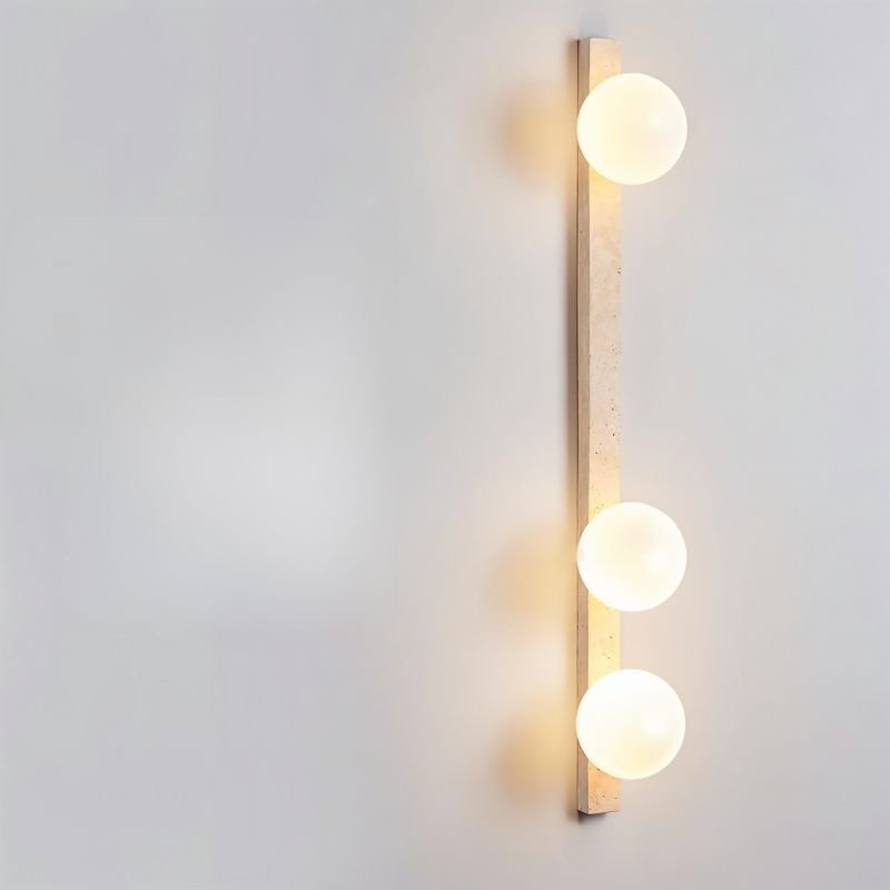 "Sleek travertine wall lamp with three frosted glass globes installed on a minimalist wall"