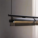 "Close-up of a modern linear pendant light showing the textured glass shades and dark metal frame."