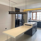 "Modern linear pendant light hanging above a kitchen island in a contemporary kitchen with light-colored walls."