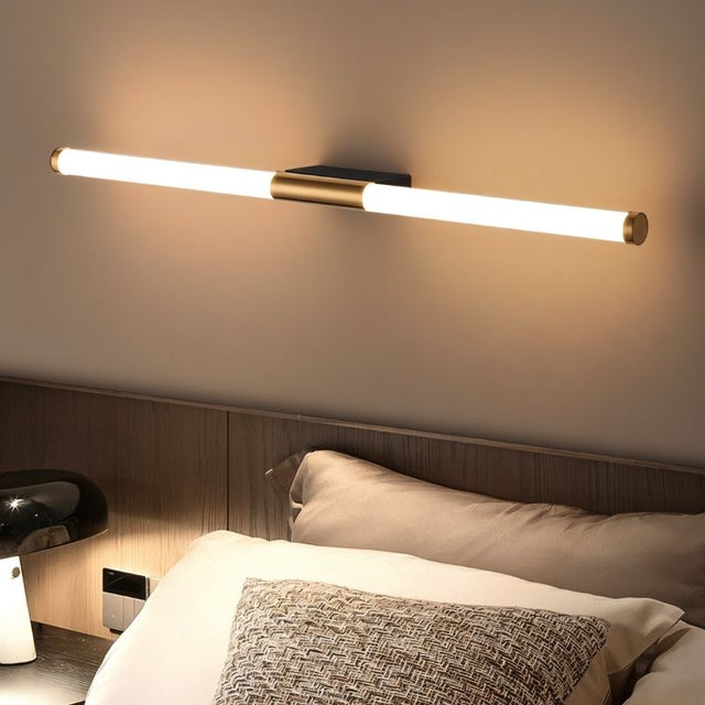 "A modern, linear LED wall lamp mounted horizontally above a bed in a bedroom."