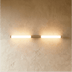 Modern brass and frosted glass bathroom vanity light fixture mounted above mirror in contemporary bathroom setting.