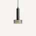 Black cylindrical pendant light with horizontal brass accents suspended against a neutral background.