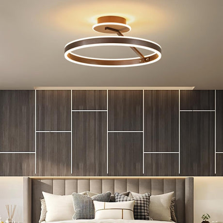 "A modern LED ceiling light with interlocking rings, illuminating a contemporary bedroom with a textured headboard."