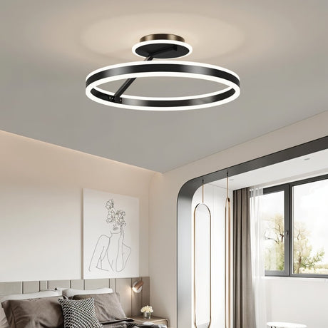 "A modern LED ceiling light with interlocking black rings, illuminating a contemporary bedroom with minimalist artwork."
