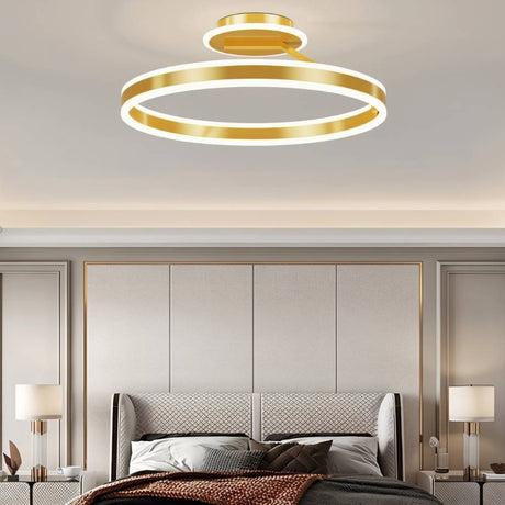 "A modern LED ceiling light with interlocking gold rings, illuminating a luxurious bedroom with a tufted headboard and matching nightstands."