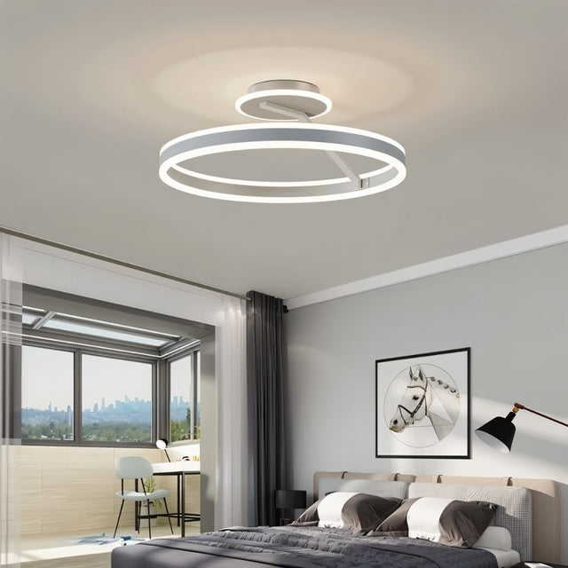"A modern LED ceiling light with interlocking white rings, illuminating a bright bedroom with a city view."