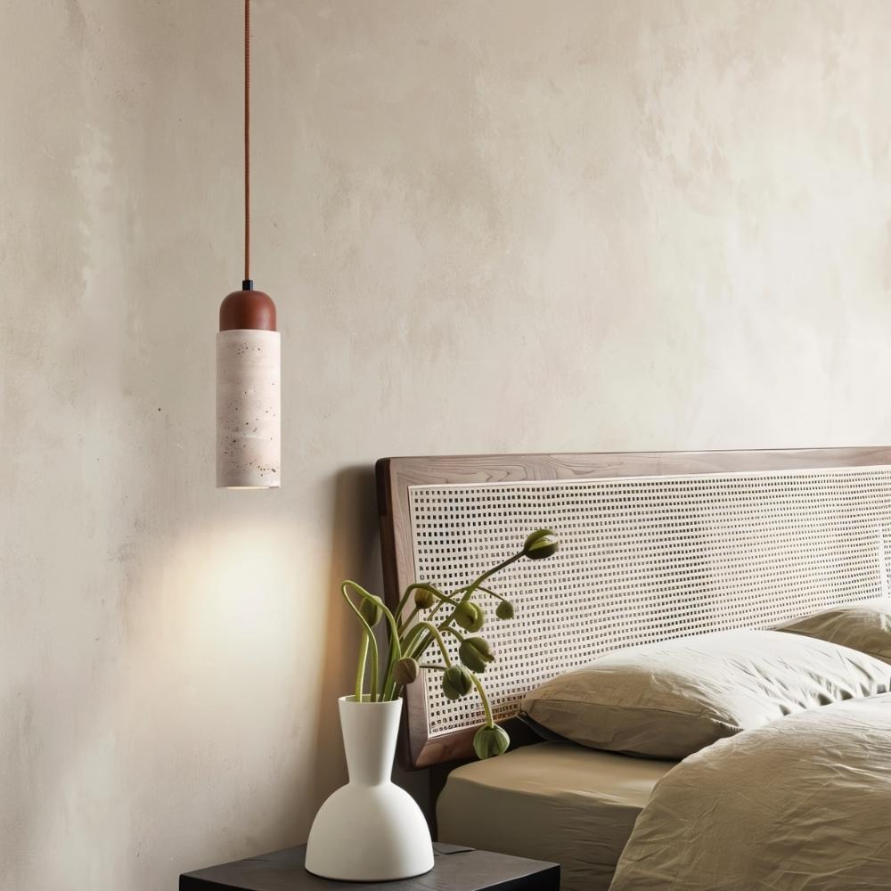 "Cylindrical travertine Gilto pendant light hanging above a bedside table in a bedroom."