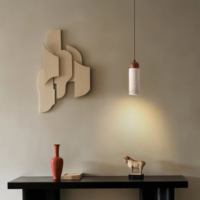 "Cylindrical travertine Gilto pendant light hanging above a console table with decorative items."