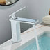 White chrome single-handle bathroom sink faucet displayed on a vanity next to a filled basin.