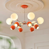 "An 8-light mid-century modern chandelier with red and white acrylic globe diffusers, hanging from a decorative ceiling."