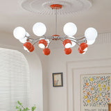 "An 8-light mid-century modern chandelier with red and white acrylic globe diffusers, hanging in a room with artwork and blinds."