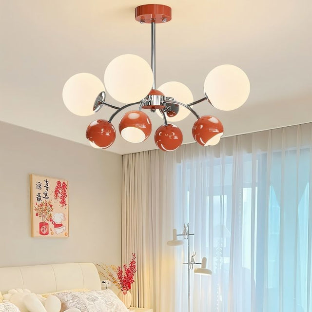 "A multi-light mid-century modern chandelier with red and white acrylic globe diffusers, hanging in a bedroom with a bed and artwork."
