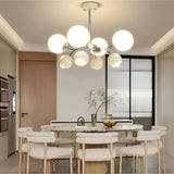 "A multi-light mid-century modern chandelier with acrylic globe diffusers, hanging above a dining table in a modern dining room."