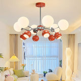 "A multi-light mid-century modern chandelier with red and white acrylic globe diffusers, hanging in a bright living room with a couch and windows."
