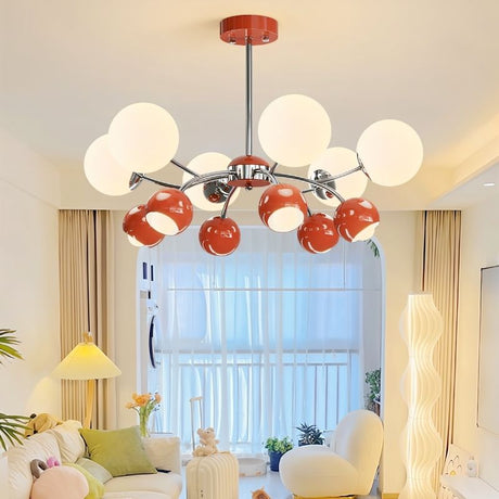 "A multi-light mid-century modern chandelier with red and white acrylic globe diffusers, hanging in a bright living room with a couch and windows."