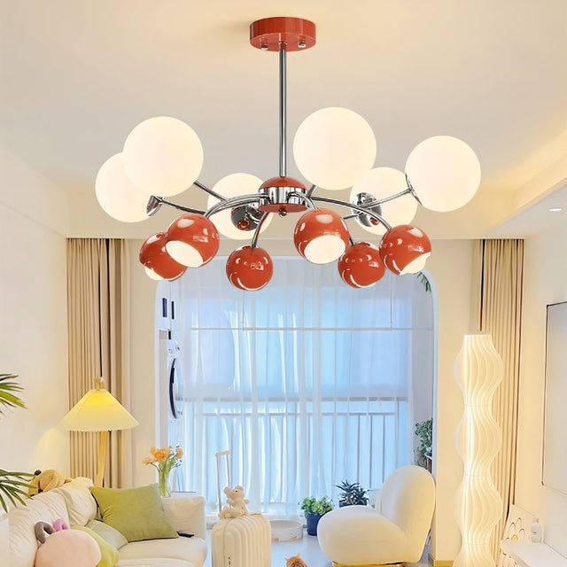 "A multi-light mid-century modern chandelier with red and white acrylic globe diffusers, hanging in a bright living room with a couch and windows."