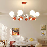 "A multi-light mid-century modern chandelier with red and white acrylic globe diffusers, hanging in a modern living room."