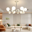 "A multi-light mid-century modern chandelier with acrylic globe diffusers, hanging in a modern living room with a white couch and decor."