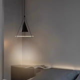 "A modern black pendant light with a cone shade and frosted glass disc in a bedroom."