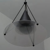 "Close-up of a modern black pendant light with a cone shade and textured glass disc."