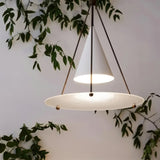 "Close-up of a modern white pendant light with a cone shade and frosted glass disc, lit."