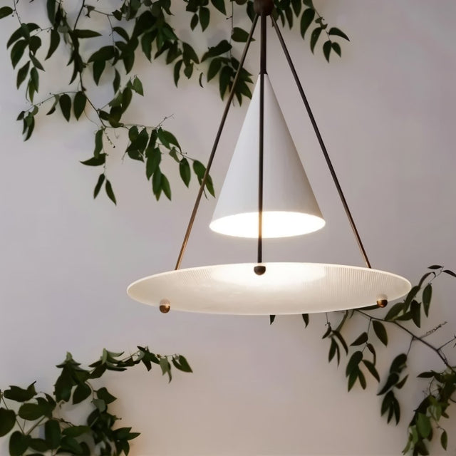 "Close-up of a modern white pendant light with a cone shade and frosted glass disc, lit."
