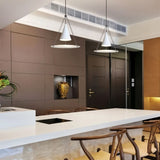 "Two modern white pendant lights with cone shades and frosted glass discs above a kitchen island."