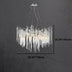 Chandelier with icicle-shaped glass elements on a chrome frame, measuring 29.92” wide and 15.74” tall against a textured wall