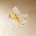 Wooden wall sconce with concrete shade and pull chain, mounted above nightstand in bedroom setting.