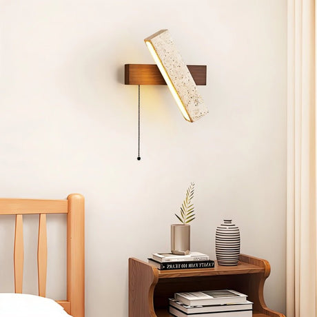 "A modern wall lamp with an angled yellow travertine shade and a rectangular wooden base, casting a warm, ambient light in a bedroom setting."