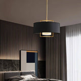 "A black pendant light with a gold frame in a bedroom setting."