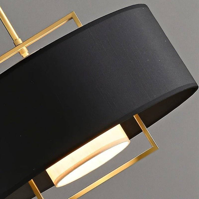 "Close-up of the black fabric shade and gold frame of a pendant light."