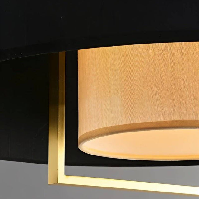 "Close-up of the black fabric shade and gold frame of a pendant light."
