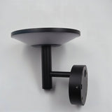 "Side view of a modern black outdoor wall lamp with a circular design, mounted on a gray wall."