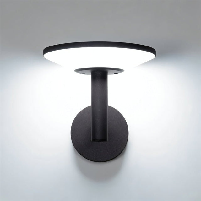 "A modern, circular outdoor wall lamp illuminating a white wall with a soft, diffused light."