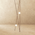 Pendant lamp with cream-colored spherical shade suspended by red cord against neutral wall, with cream upholstered chair in s