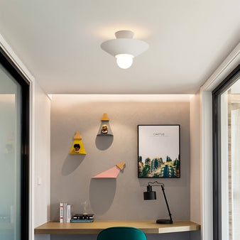 "The Glome Ceiling Lamp installed in a stylish home office, featuring a conical aluminum design with a central globe bulb, providing minimalist and efficient lighting."