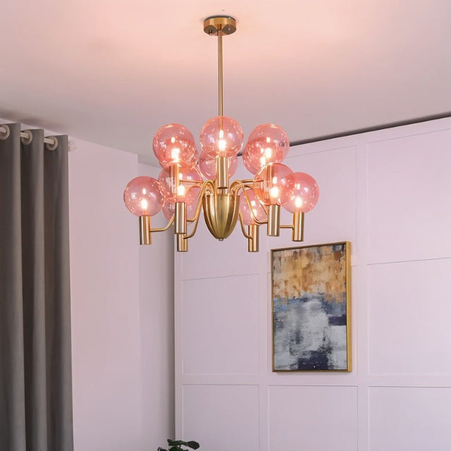 Gloral Chandelier with twelve pink glass globes and gold frame, illuminating a contemporary living space with ambient lighting.
